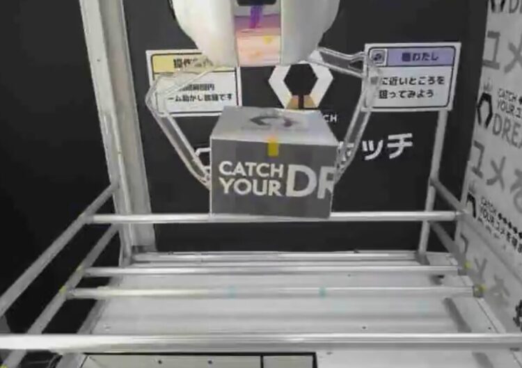 橋渡し台でクレーンアームが景品の箱をつかんでいる様子のアップ画像
